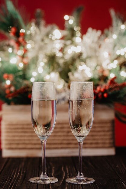 Composición navideña árboles de navidad decorados con luces doradas, guirnaldas, juguetes y copas de champán vacías.