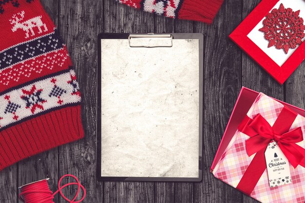 Composición navideña con suéter, portapapeles y regalos