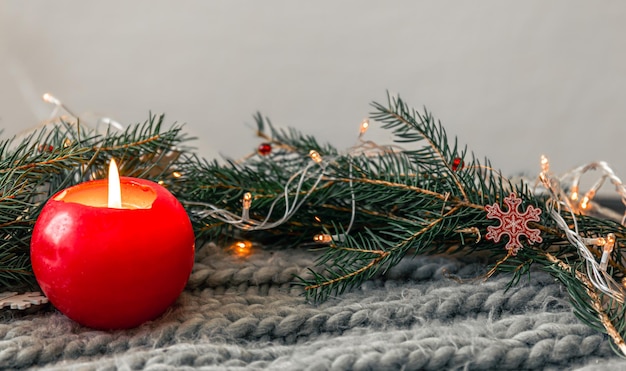 Composición navideña con una vela un elemento de punto con ramas de abeto