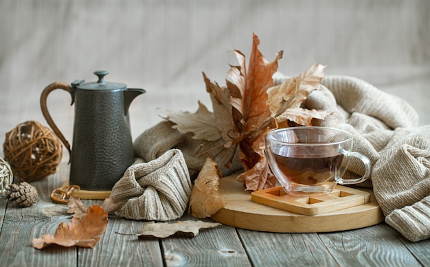 Composición otoñal con una taza de té y detalles decorativos de confort en el hogar.