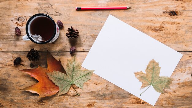 Composición de otoño con hojas y té en el fondo de madera