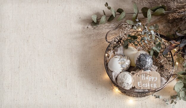 Composición de Pascua con huevos decorativos en una canasta en un espacio de copia de superficie ligera con textura.