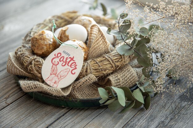 Composición de Pascua con huevos de Pascua decorados y nido decorativo sobre una superficie de madera