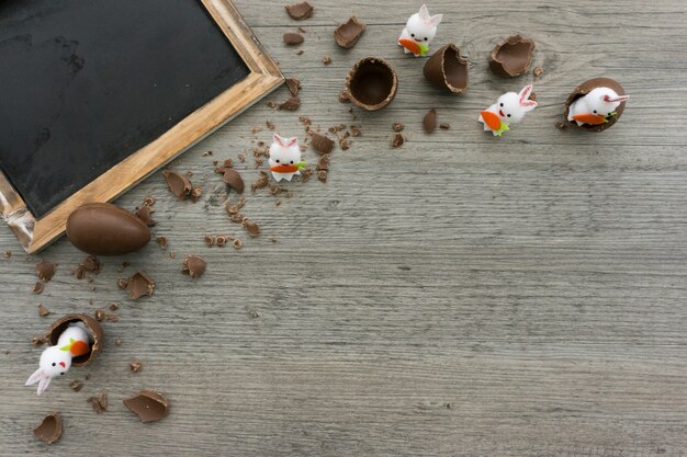 Composición de pascua con pizarra en blanco, huevos de chocolate y conejos decorativos