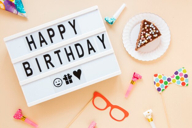 Composición con pastel en rodajas y letras de cumpleaños