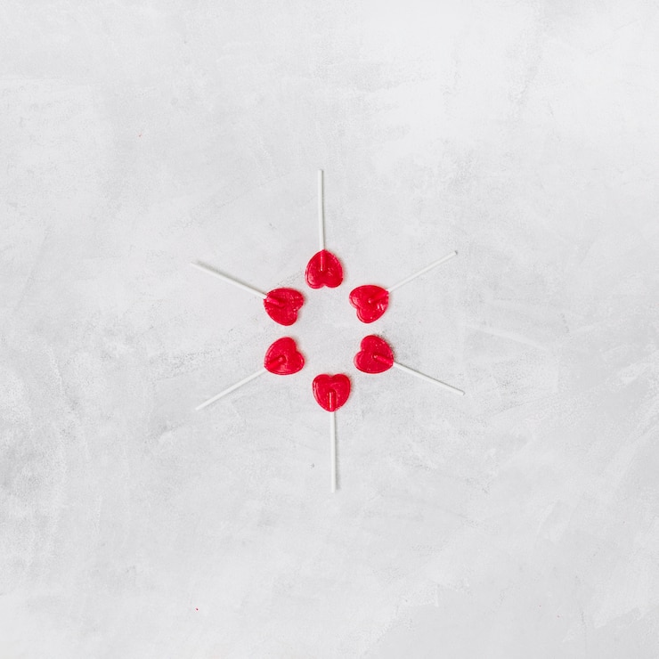 Foto gratuito composición de piruletas en forma de corazón en varitas