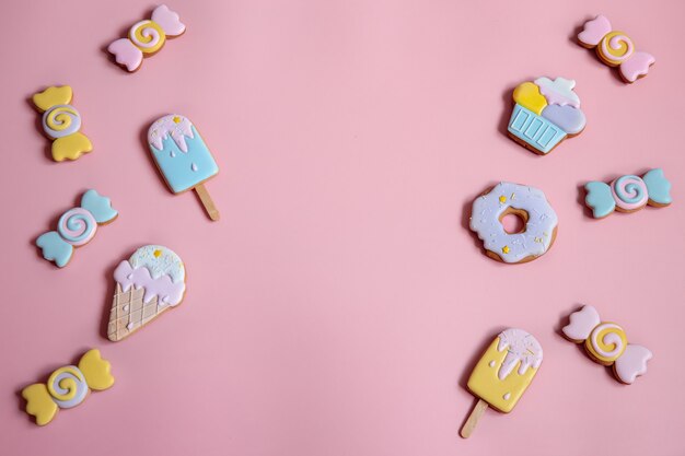 Composición plana con galletas de jengibre glaseadas brillantes en el espacio de copia de fondo rosa.