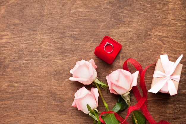 Composición plana laicos con rosas y anillo de compromiso.