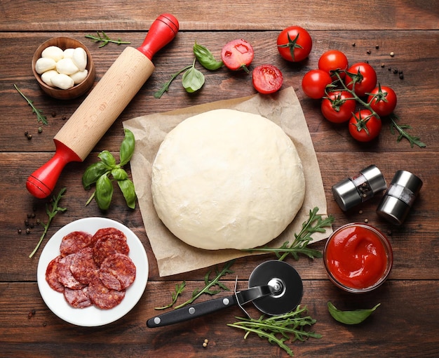 Foto gratuita composición plana con masa e ingredientes frescos para pizza de pepperoni en mesa de madera
