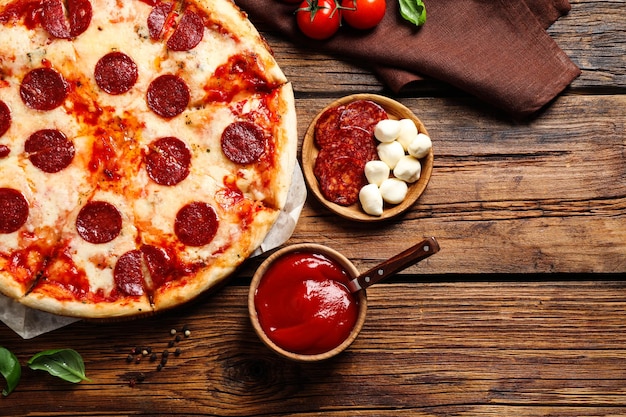 Composición plana con pizza de pepperoni caliente en la mesa de madera