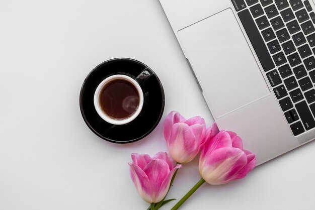 Composición de portátil con tulipanes y taza de café.