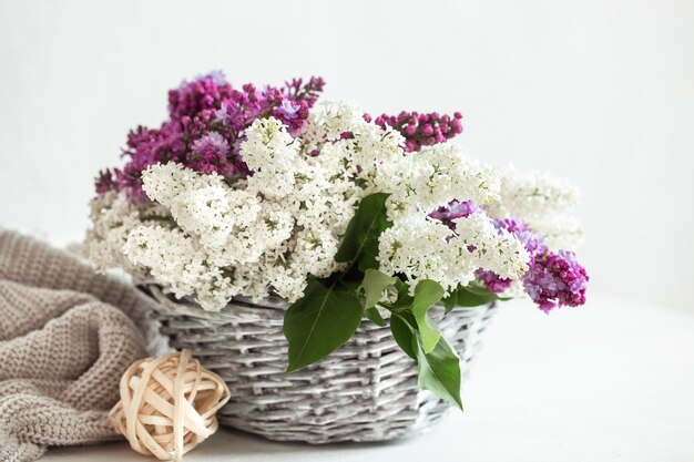 Composición de primavera con flores de color lila en una cesta de mimbre.