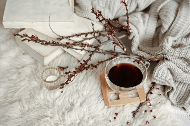 Composición de primavera con una taza de té, ramas en flor y detalles decorativos.