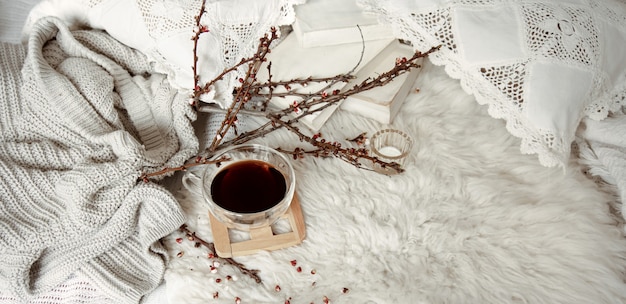 Composición de primavera con una taza de té, ramas en flor y un elemento de punto.