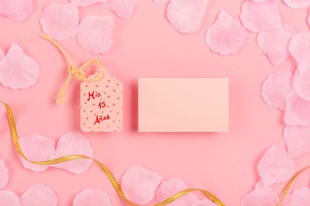 Composición de quinceañera con tarjeta vacía sobre fondo rosa