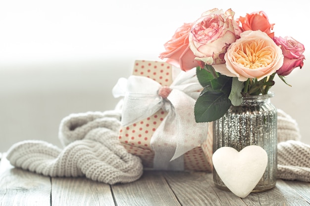 Composición con un ramo de rosas en un jarrón de vidrio con caja de regalo