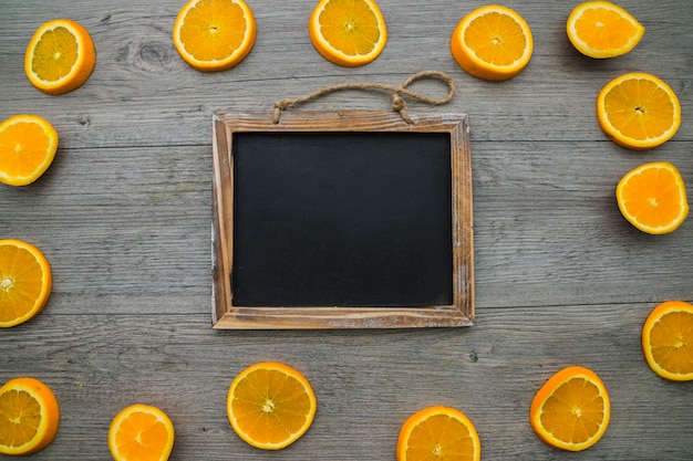 Composición con rodajas de naranja y pizarra en blanco