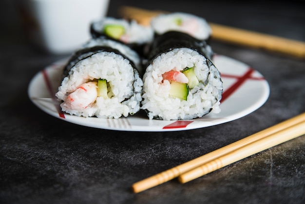 Composición de rollos de sushi en plato y palillos.