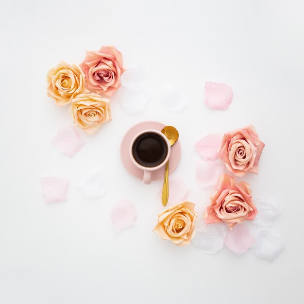 Composición romántica hecha con una taza rosa de café y rosas.