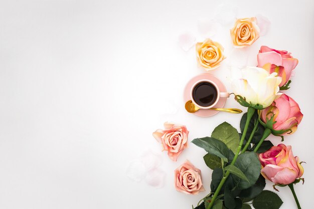 Composición romántica con rosas, pétalos y una taza de café rosa con espacio de copia