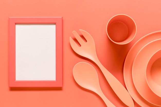 Composición rosa con marco vacío y platos de plástico.