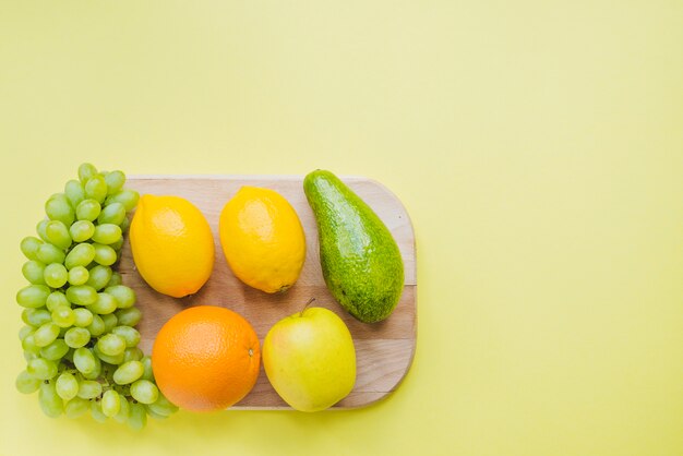 Composición saludable con tabla de cortar y varias frutas