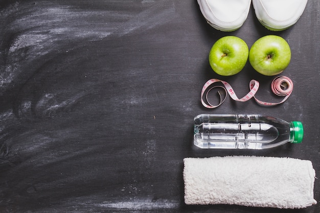 Composición saludable con toalla, manzanas y botella de agua