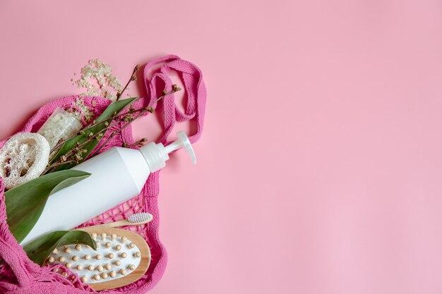 Composición de spa plana con artículos de higiene personal y accesorios de baño en una bolsa de hilo.