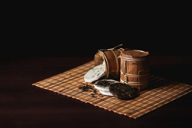 La composición de té de puer chino lleno en una estera de bambú.