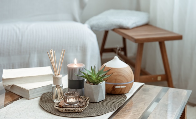 Composición con varitas de incienso, difusor, velas y libros sobre la mesa en el interior de la habitación.