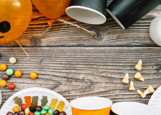 Composición con vasos de papel dispersos y dulces en la mesa de madera