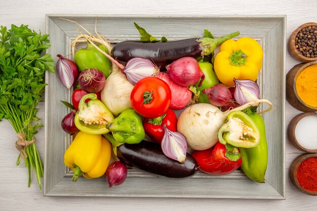 Composición vegetal de la vista superior con verduras y condimentos en la mesa blanca