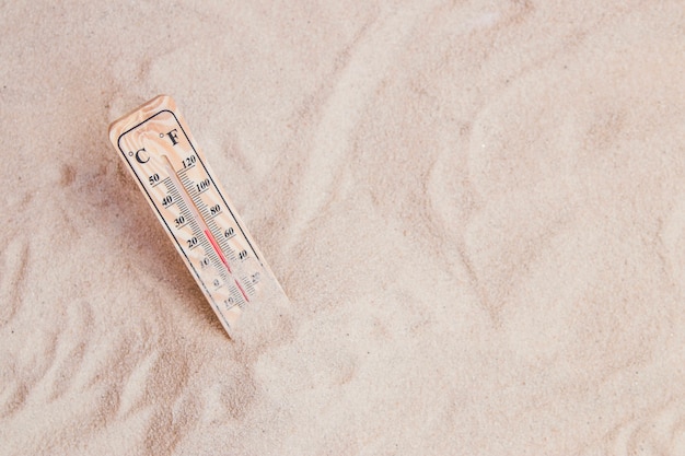 Composición veraniega con arena y termómetro