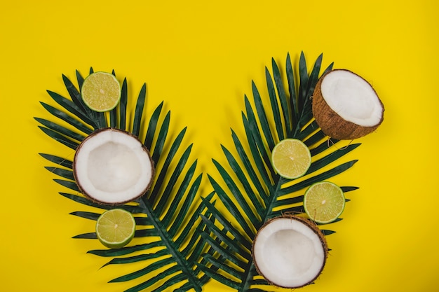 Composición veraniega con cocos, limas y hojas de palma