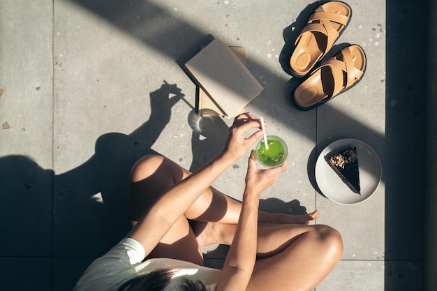 Composición de verano con zapatillas libros pastel y limonada en manos femeninas