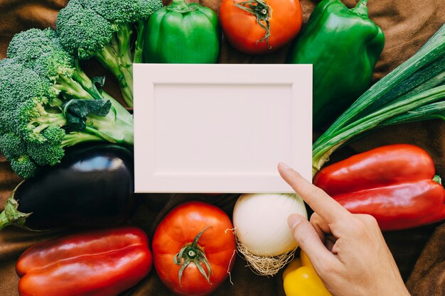 Composición de verduras con dedo apuntando a marco