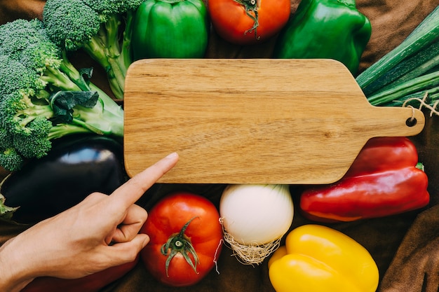 Composición de verduras con dedo apuntando a tabla