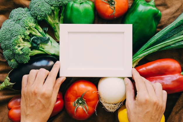 Composición de verduras con manos y marco