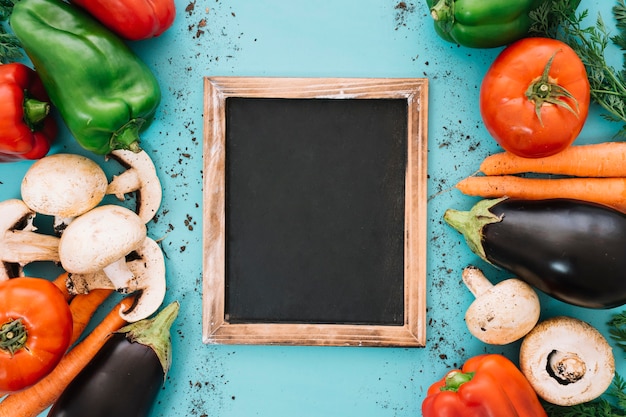 Foto gratuita composición de verduras con pizarra en medio