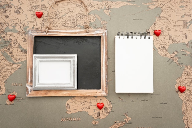 Foto gratuita composición de viaje con corazones decorativos y libreta en blanco