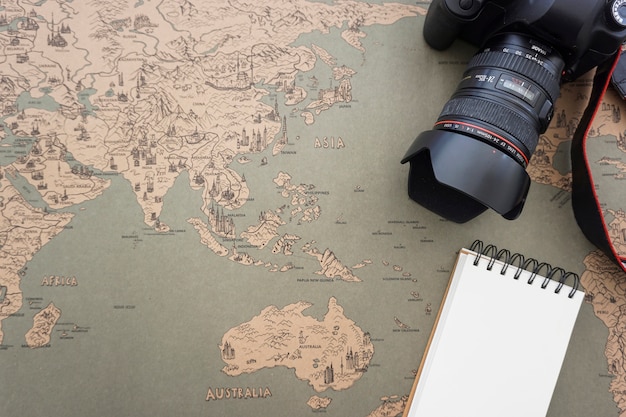 Composición de viaje con mapa vintage, cámara y cuaderno en blanco