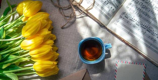Composición vintage con una taza de té, tulipanes y notas planas.