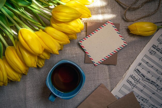 Composición vintage con una taza de té, tulipanes y notas planas.