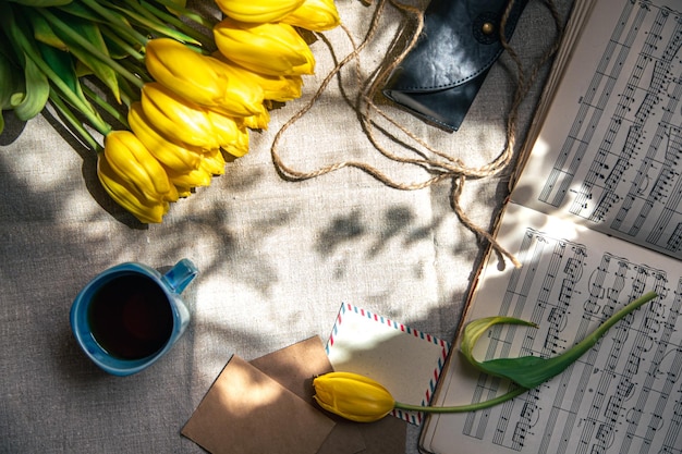 Composición vintage con una taza de té, tulipanes y notas planas.