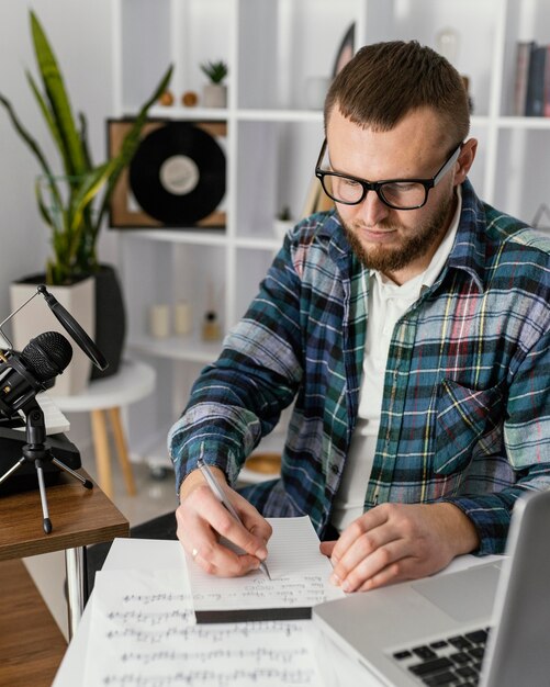 Compositor de tiro medio escribiendo en un portátil