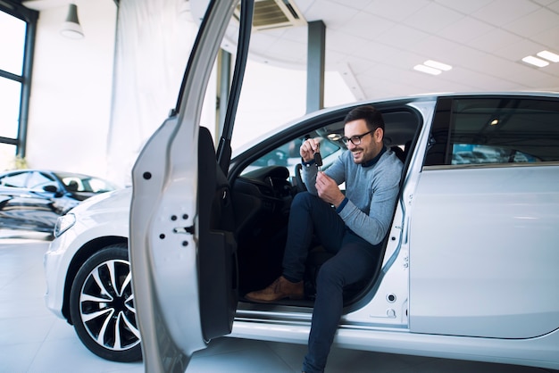 Comprador de coche sosteniendo las llaves del vehículo nuevo y sonriendo