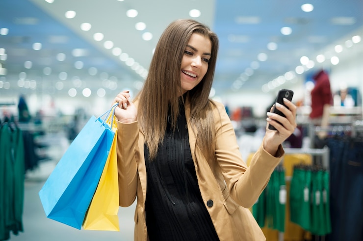Foto gratuito compradora femenina alegre enviando mensajes de texto en el teléfono móvil