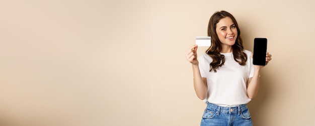 Foto gratuita compras en línea y concepto de personas joven hermosa mujer que parece feliz mostrando descuento de tarjeta de crédito