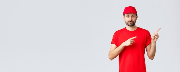 Compras en línea, entrega durante la cuarentena y concepto de comida para llevar. Mensajero barbudo confiado en gorra y camiseta de uniforme rojo, cámara sonriente, dar dirección, señalar con el dedo a la derecha, informar a los clientes.