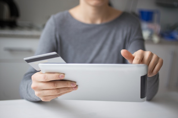 Compras de la mujer usando la tableta y la tarjeta de crédito